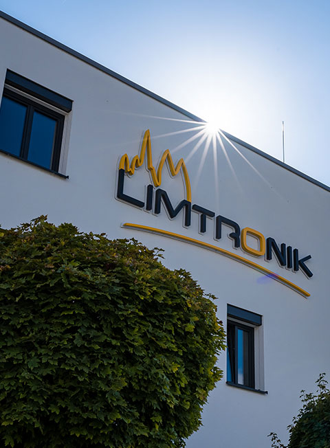 Sunlight shines on the Limtronik company building with its large logo on the facade.