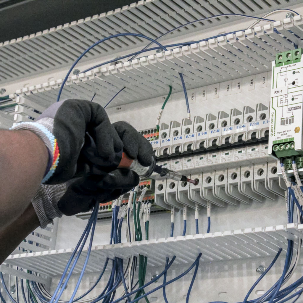 Electricians wire cables in the control cabinet.