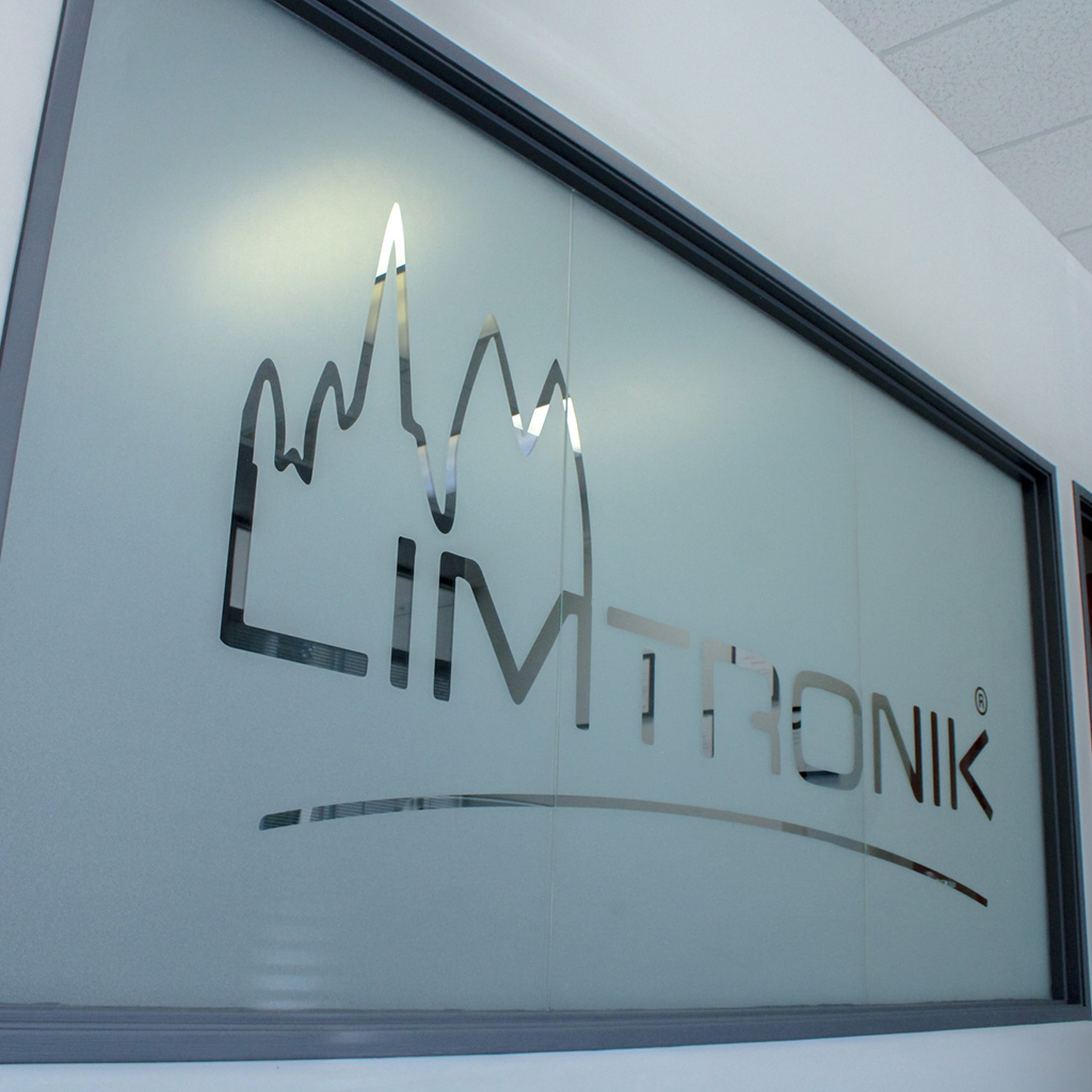 Limtronik logo as lettering and symbol on a glass wall in the company building.